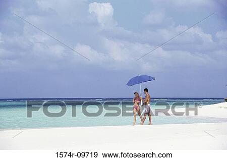 Stock Photo - Young couple walking together at the beach. Fotosearch