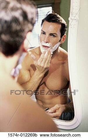 Stock Image - Young man applying shaving cream to his face. Fotosearch