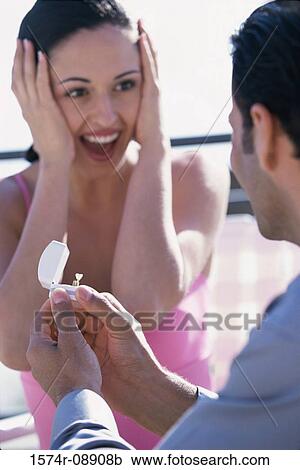 Stock Image - Young man giving a young woman an engagement ring. Fotosearch