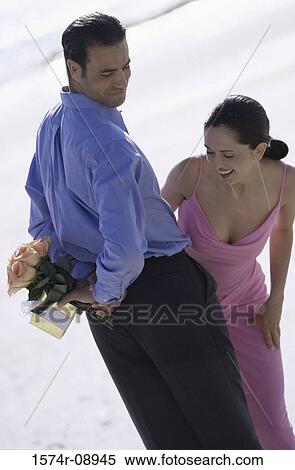 Young man hiding a bouquet of flowers from a young woman View Large Photo Image Stock Photography - Young man hiding a bouquet of flowers from a young woman. Fotosearch