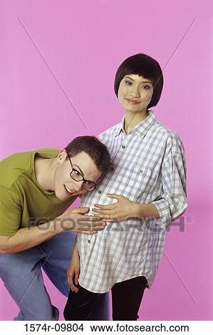 Young man listening to a young pregnant woman's abdomen View Large Photo Image Picture - Young man listening to a young pregnant woman's abdomen. Fotosearch