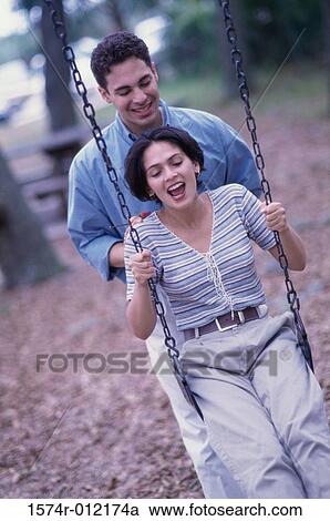 Young man pushing a young woman on a swing View Large Photo Image Stock Image - Young man pushing a young woman on a swing. Fotosearch
