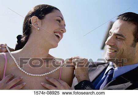 Young man putting a pearl necklace on a young woman View Large Photo Image Stock Photography - Young man putting a pearl necklace on a young woman. Fotosearch