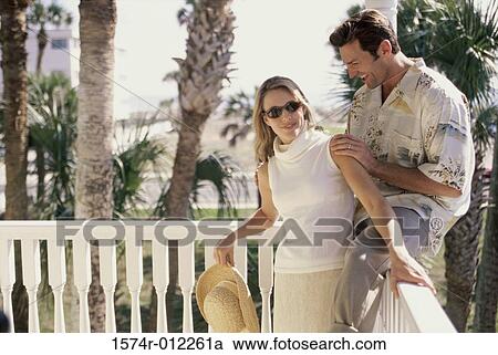 Young man sitting on the balustrade with a young woman standing in front of him View Large Photo Image Stock Image - Young man sitting on the balustrade with a young woman standing in front of him. Fotosearch