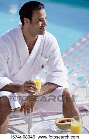 Young man sitting poolside with a glass of orange juice View Large Photo Image Stock Photograph - Young man sitting poolside with a glass of orange juice. Fotosearch