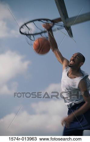Stock Image - Young man slam dunking. Fotosearch