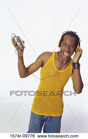 Young man wearing headphones singing with his eyes closed View Large Photo Image Stock Photograph - Young man wearing headphones singing with his eyes closed. Fotosearch