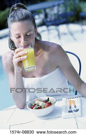 Stock Image - Young woman drinking a glass of orange juice. Fotosearch