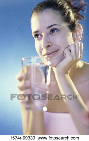 Young woman holding a glass of water View Large Photo Image Stock Photo - Young woman holding a glass of water. Fotosearch