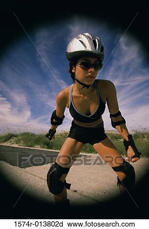 Stock Image - Young woman inline skating on a road. Fotosearch