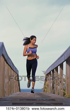 Young woman jogging on a bridge View Large Photo Image Stock Image - Young woman jogging on a bridge. Fotosearch