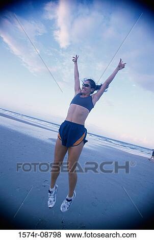Young woman jumping on the beach View Large Photo Image Stock Photo - Young woman jumping on the beach. Fotosearch