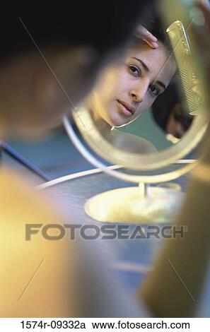 Stock Image - Young woman looking into a mirror. Fotosearch