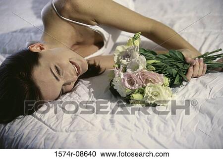 Young woman lying down holding a bouquet of flowers View Large Photo Image Stock Image - Young woman lying down holding a bouquet of flowers. Fotosearch