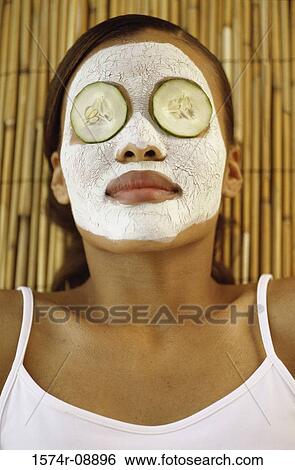 Stock Photograph - Young woman lying down wearing a facial mask. Fotosearch