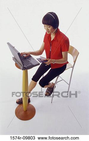 Young woman operating a laptop holding a credit card View Large Photo Image Stock Image - Young woman operating a laptop holding a credit card. Fotosearch