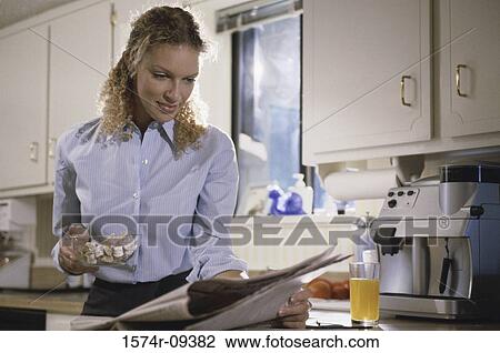 Stock Image - Young woman reading a newspaper. Fotosearch