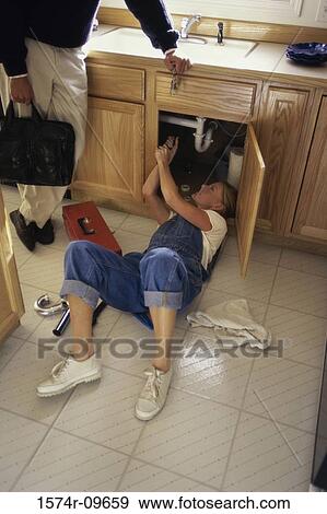 Young woman repairing the plumbing under a kitchen sink View Large Photo Image Stock Photo - Young woman repairing the plumbing under a kitchen sink. Fotosearch