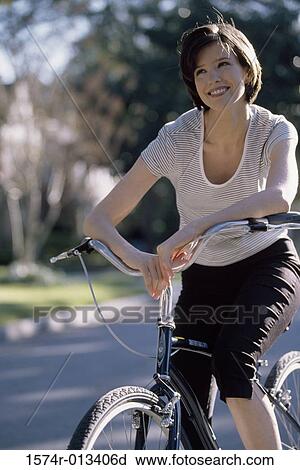 Stock Image - Young woman riding a bicycle. Fotosearch