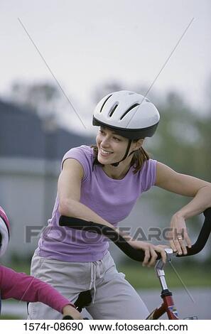 Stock Image - Young woman riding a bicycle. Fotosearch