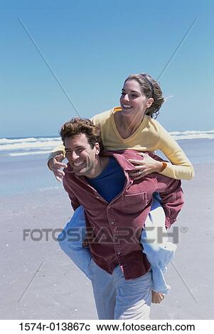 Young woman riding piggyback on a young man View Large Photo Image Stock Image - Young woman riding piggyback on a young man. Fotosearch