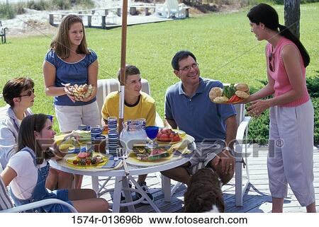 Young woman serving food to a family on a deck View Large Photo Image Stock Image - Young woman serving food to a family on a deck. Fotosearch