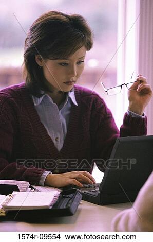 Picture - Young woman sitting in front of a laptop computer. Fotosearch
