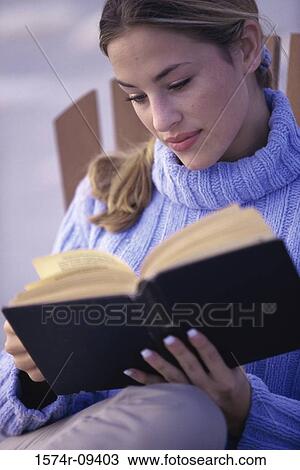 Young woman sitting outdoors reading a book View Large Photo Image Stock Image - Young woman sitting outdoors reading a book. Fotosearch
