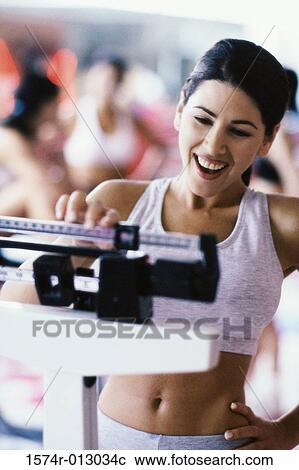 Young woman standing on a weight scale View Large Photo Image Stock Image - Young woman standing on a weight scale. Fotosearch