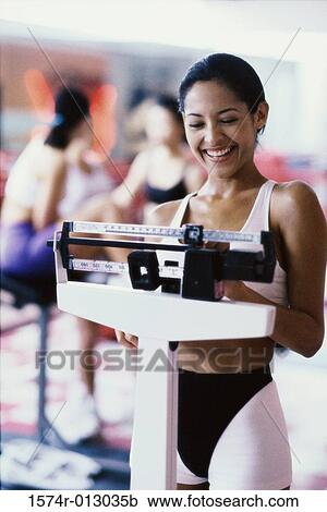 Young woman standing on a weight scale View Large Photo Image Stock Image - Young woman standing on a weight scale. Fotosearch