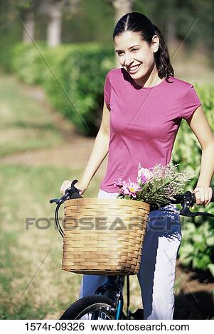 Young woman standing with a bicycle View Large Photo Image Stock Photograph - Young woman standing with a bicycle. Fotosearch