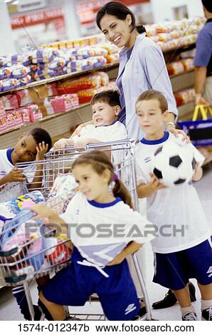 Stock Image - Young woman with four children in a supermarket. Fotosearch