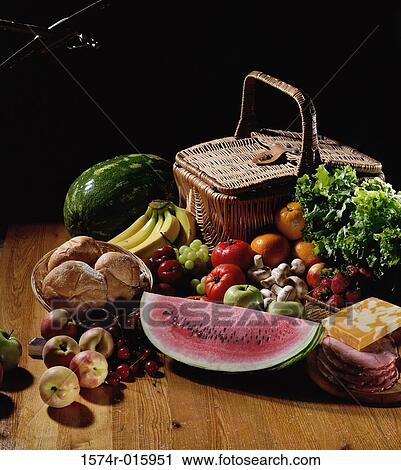 Stock Image - Basket next to assorted fruits and vegetables. Fotosearch