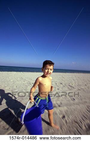 Boy carrying a bucket on the beach View Large Photo Image Stock Photograph - Boy carrying a bucket on the beach. Fotosearch