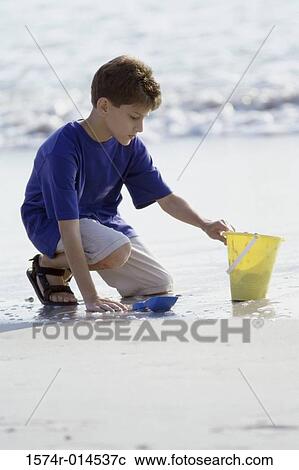 Boy digging sand with a shovel on the beach View Large Photo Image Stock Image - Boy digging sand with a shovel on the beach. Fotosearch