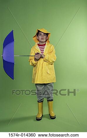 Stock Image - Boy wearing a raincoat and holding an umbrella. Fotosearch