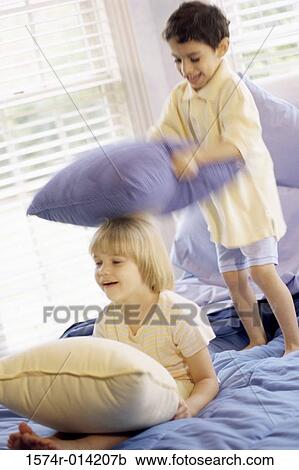 Brother and sister having a pillow fight on the bed View Large Photo Image Stock Image - Brother and sister having a pillow fight on the bed. Fotosearch