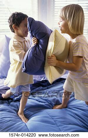 Brother and sister having a pillow fight on the bed View Large Photo Image Stock Image - Brother and sister having a pillow fight on the bed. Fotosearch