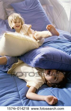 Brother and sister having a pillow fight on the bed View Large Photo Image Stock Photo - Brother and sister having a pillow fight on the bed. Fotosearch