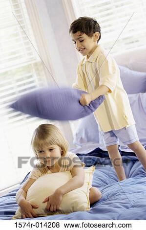 Brother having a pillow fight with his sister View Large Photo Image Stock Photo - Brother having a pillow fight with his sister. Fotosearch