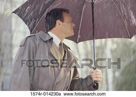 Stock Image - Businessman holding an umbrella in the rain. Fotosearch