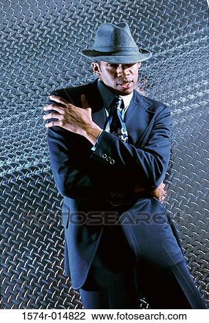 Stock Image - Businessman standing in front of a metallic wall. Fotosearch