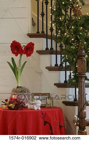 Stock Image - Candle and a potted plant with a picture frame on a table beside a staircase. Fotosearch