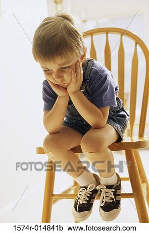 Stock Image - Close-up of a boy sitting on a chair. Fotosearch