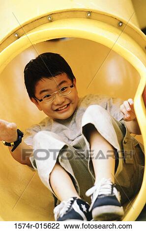 Stock Image - Close-up of a boy sliding down a slide. Fotosearch