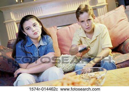 Stock Image - Close-up of a brother and sister watching television. Fotosearch