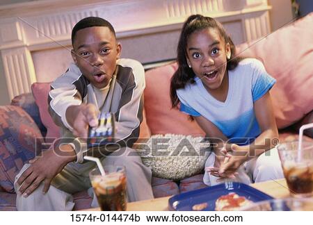 Stock Image - Close-up of a brother and sister watching television. Fotosearch