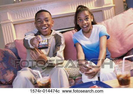 Stock Image - Close-up of a brother and sister watching television. Fotosearch