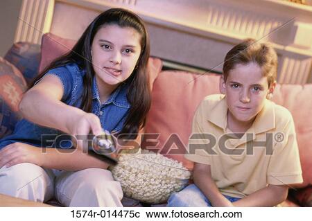Stock Image - Close-up of a brother and sister watching television. Fotosearch