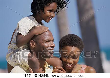 Close-up of a daughter riding on her father's shoulders on the beach with her mother standing beside them View Large Photo Image Stock Image - Close-up of a daughter riding on her father's shoulders on the beach with her mother standing beside them. Fotosearch